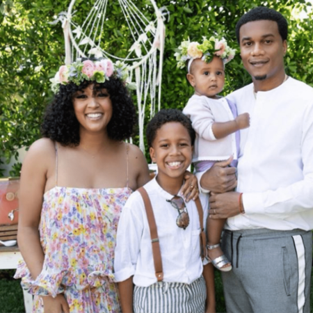 Cory Hardrict in a white t-shirt poses a picture  with his children and wife.